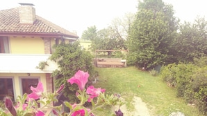A house with a tiled roof, a brick chimney, and a garden with a lawn and trees. - Ostello Le Tre Corone (Calendasco)