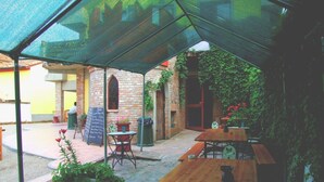 An outdoor patio area with wooden tables and benches, a chalkboard menu, and potted plants. - Ostello Le Tre Corone (Calendasco)