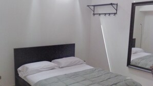 A bedroom with a bed, a ceiling light, a mirror, and a wall-mounted rack. - Ostello Le Tre Corone (Calendasco)