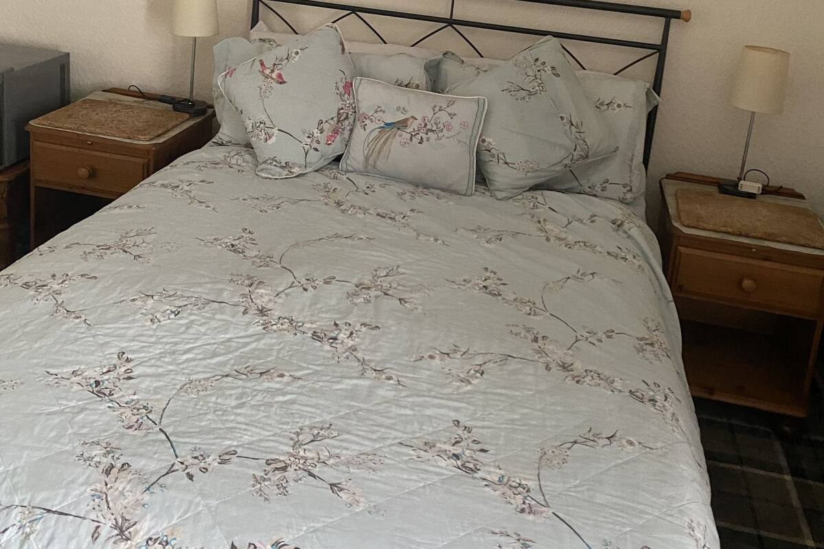A bedroom with a bed, two nightstands, a mirror, and heart-shaped wall decorations.