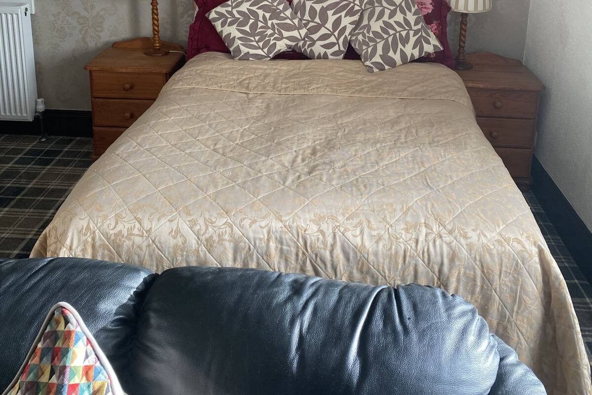 A neatly made bed with a quilted headboard, two bedside tables with lamps, and a patterned wall.
