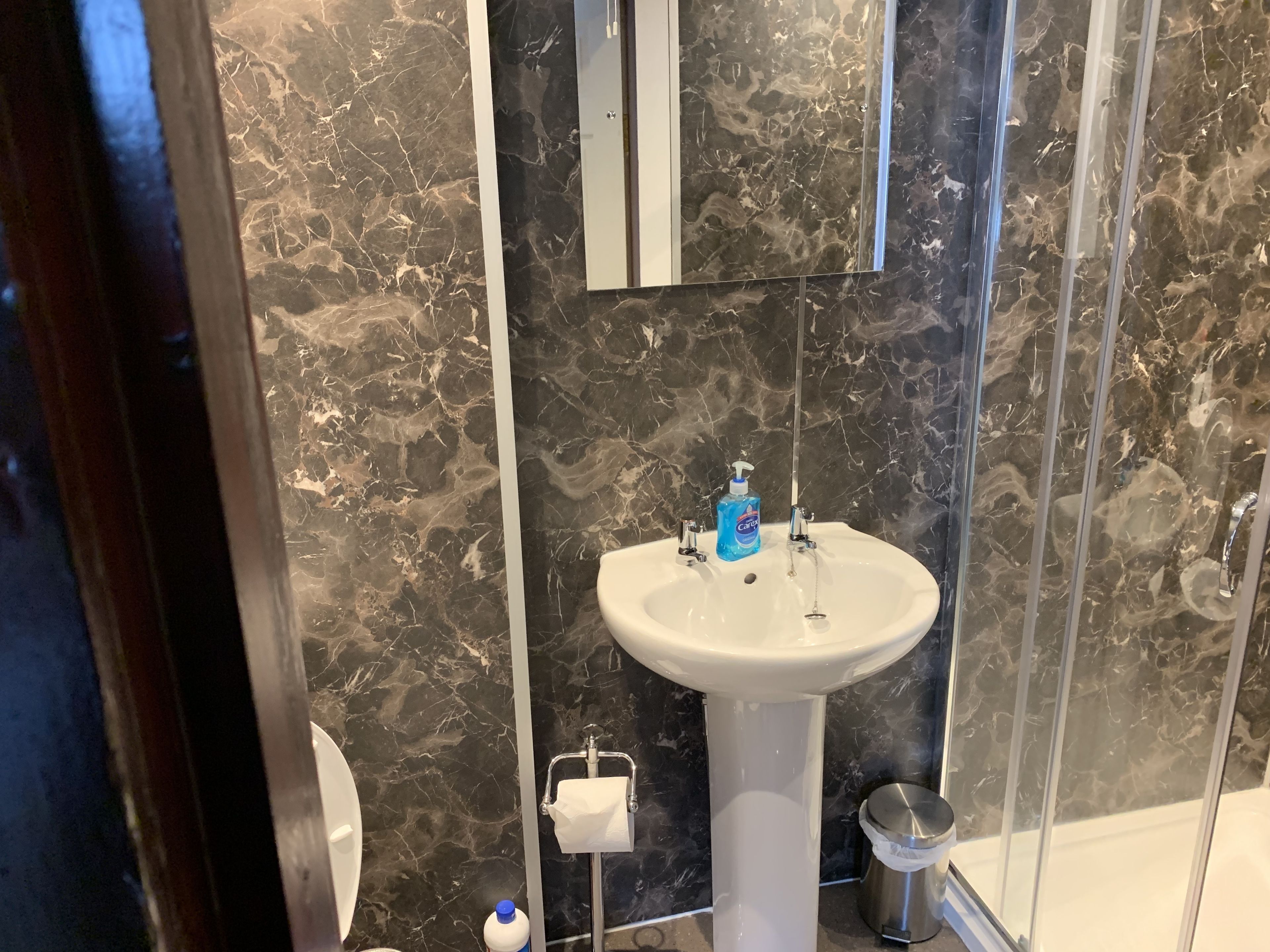 A bathroom with a white sink, a mirror, a toilet, and a shower area.