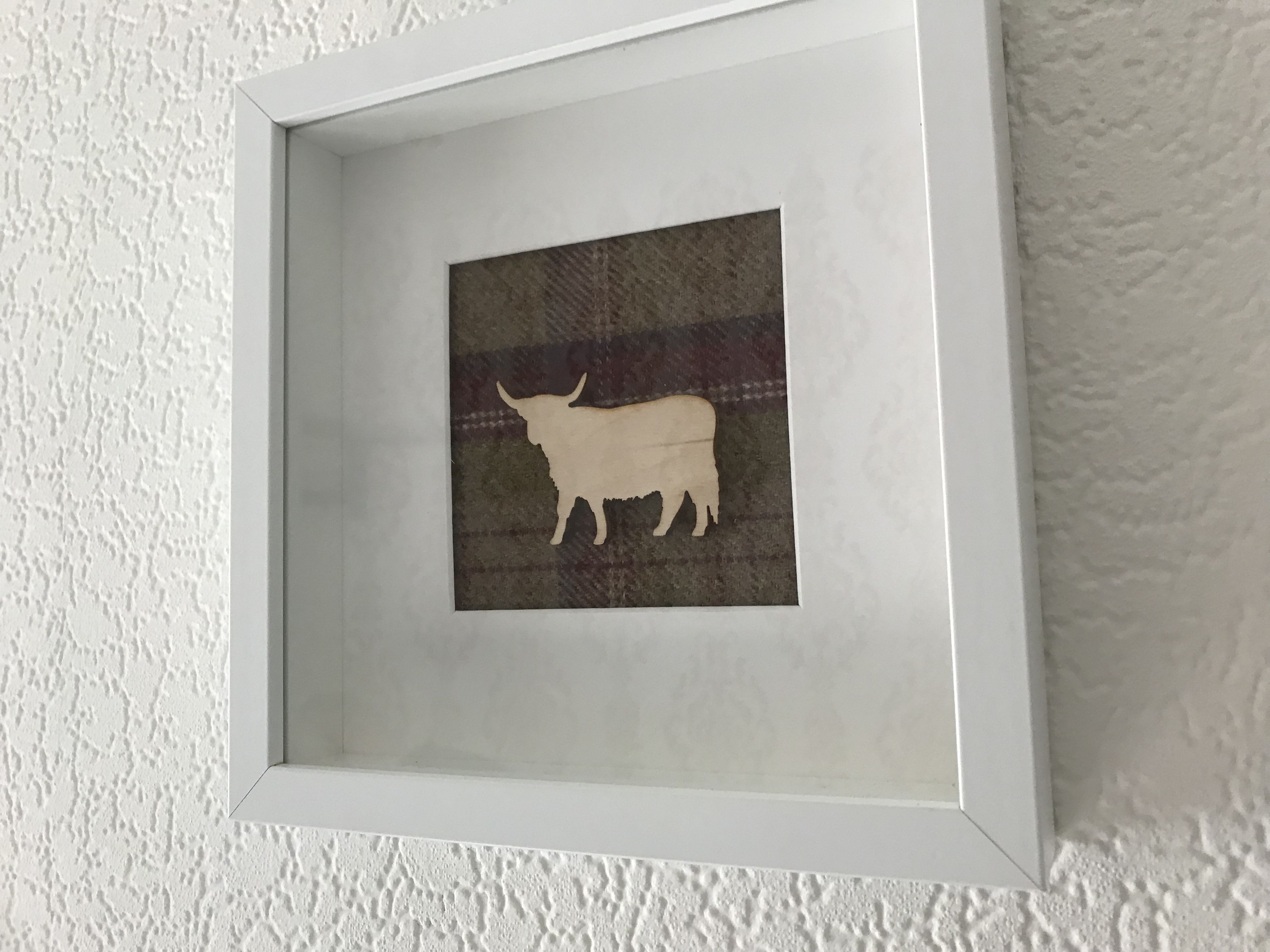 A framed artwork of a bull on a textured background.