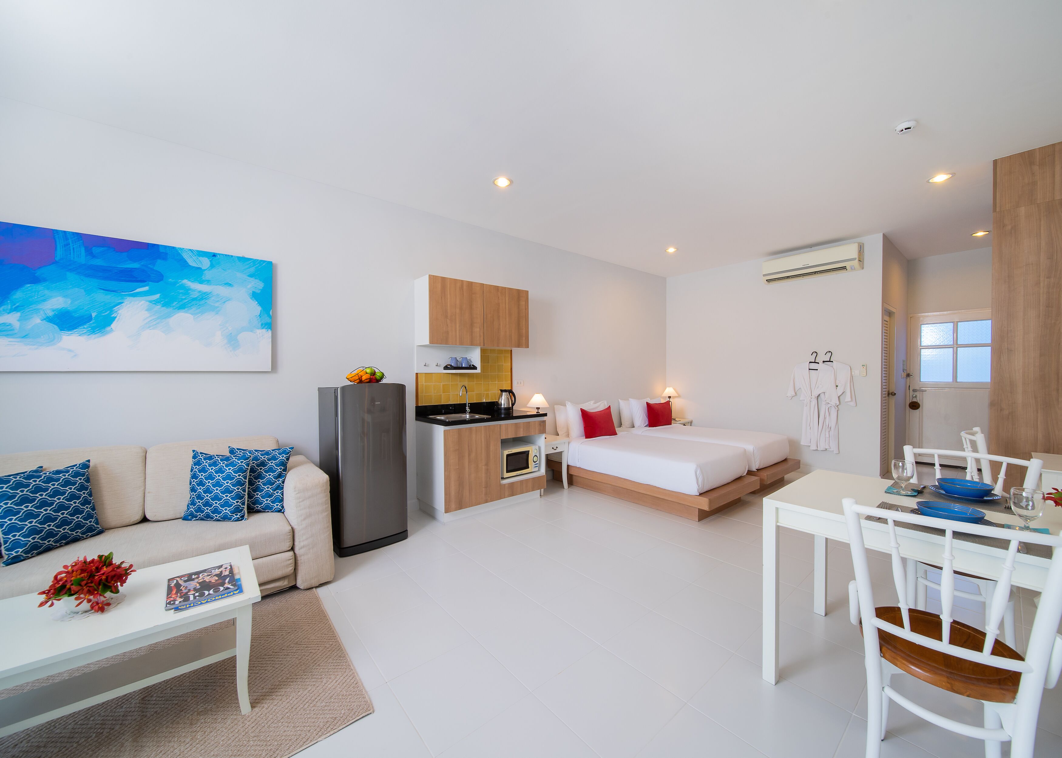 Une pièce moderne et bien éclairée, comprenant un canapé, une table à manger avec des chaises, un coin cuisine et un lit.