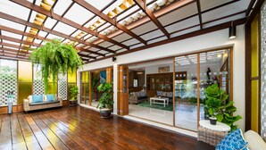 A spacious indoor area with a wooden floor, large sliding glass doors, and potted plants. - Blu Marine Hua Hin Resort and Villas (Hua Hin)