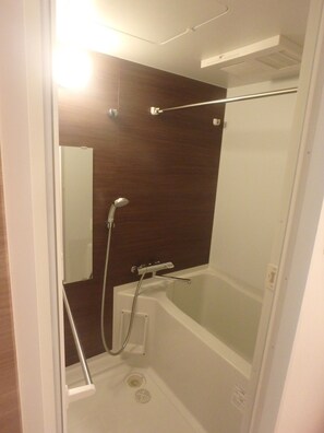 A small, enclosed shower area with a glass door, a white bathtub, and a wooden wall. - YADO at Shinsaibashi Namba ExMin (Osaka)