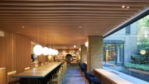 A modern library with a long wooden table and chairs, a circular reading area, and bookshelves. - Hakone Yutowa (Hakone)