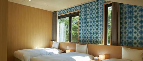 A hotel room with two beds, a large window, and a view of trees.