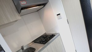 A compact kitchen with a gas stove, stainless steel sink, and light-colored cabinetry. - YADO at Tennouji Namba ExTen (Osaka)