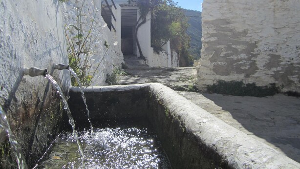 A narrow alleyway with a water feature and white buildings. - Hostal Las Terrazas de la Alpujarra (Bubion)