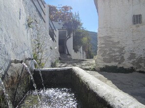 Un callejón estrecho con una fuente y edificios blancos.