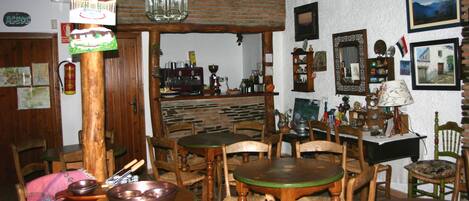 Un interior rústico con mesas y sillas de madera, una zona de bar y diversas decoraciones.