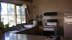 A kitchen with a window, a stove, a sink, and a refrigerator. - The Beach Break (SMITHS BEACH)
