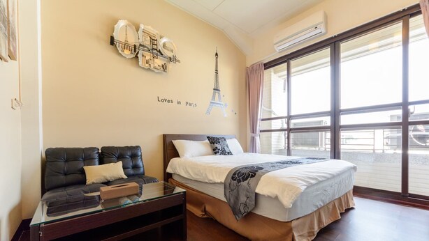 A hotel room with a bed, a sofa, a glass coffee table, and a large window with a view. - Seven Dwarfs (Puli)