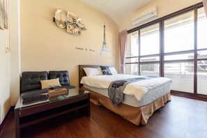 A hotel room with a bed, a sofa, a glass coffee table, and a large window with a view. - Seven Dwarfs (Puli)
