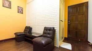 A room with two leather chairs, a small table, and a white brick wall. - Seven Dwarfs (Puli)