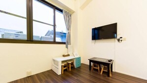 A room with a desk, a chair, a TV mounted on the wall, and a window with a curtain. - Seven Dwarfs (Puli)