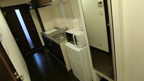 Cozinha compacta com pia, micro-ondas e geladeira.