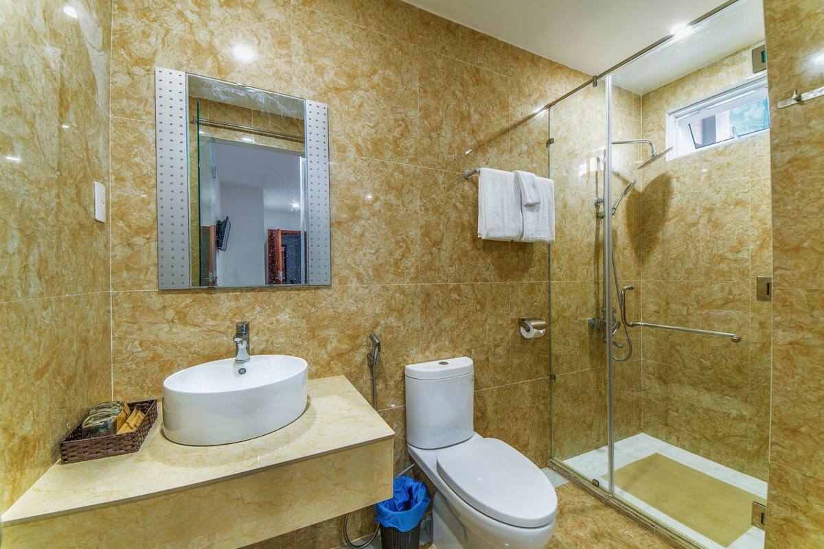 Un baño con lavamanos, inodoro y ducha con mampara de vidrio.