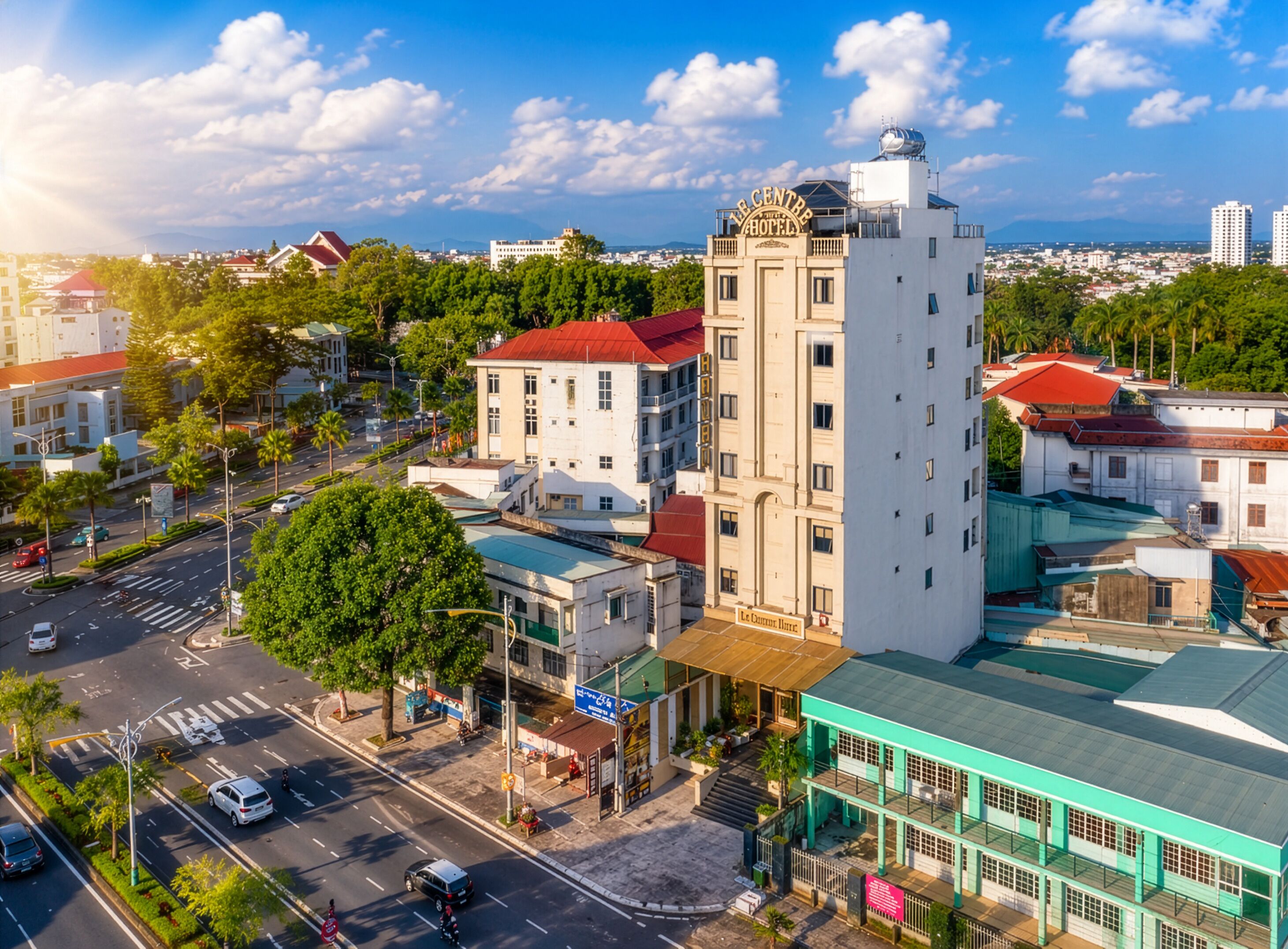 A hotel with a prominent tower, a street view with cars, and surrounding greenery.
