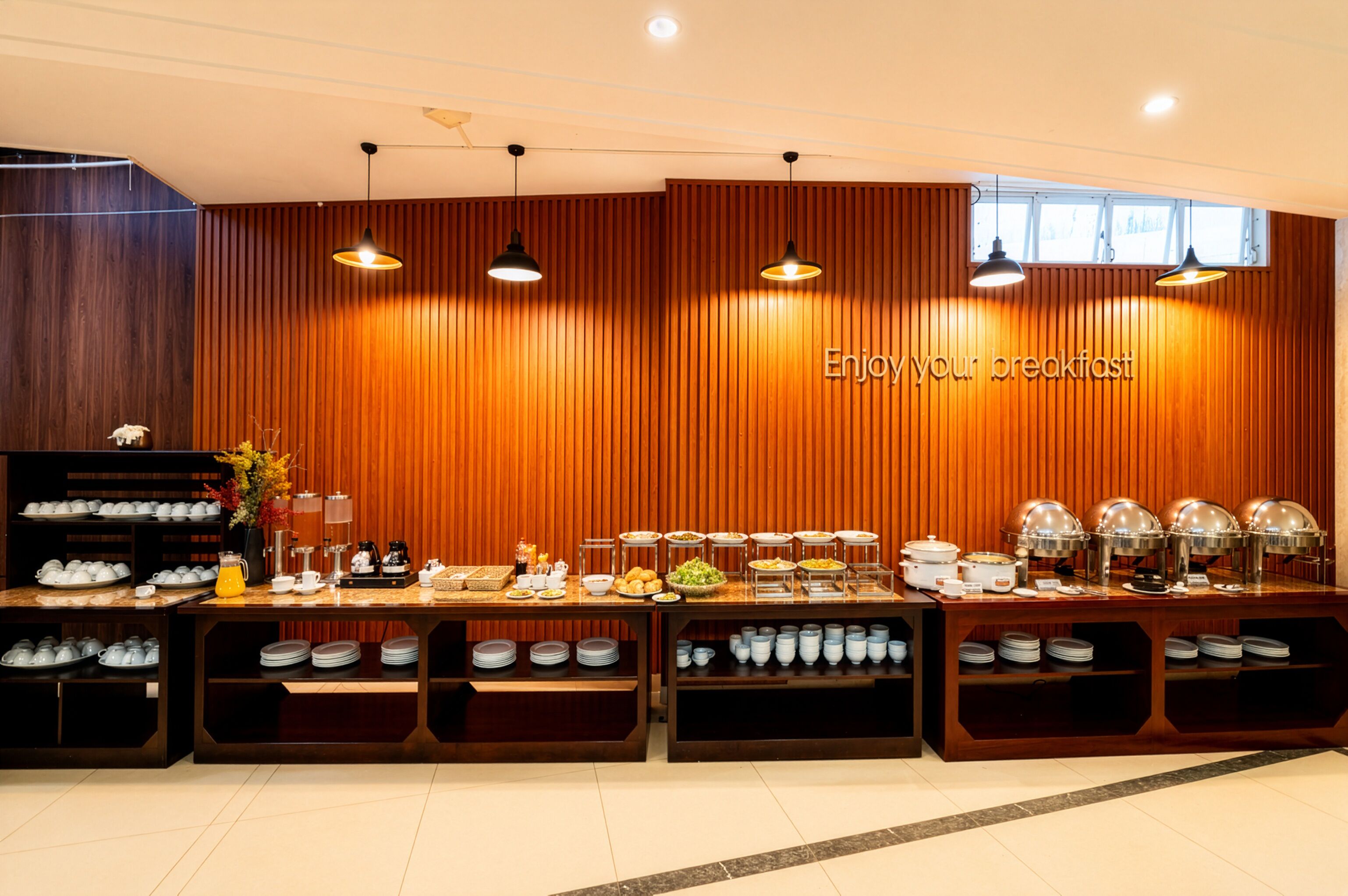 A breakfast buffet area with a wooden wall and multiple serving stations.