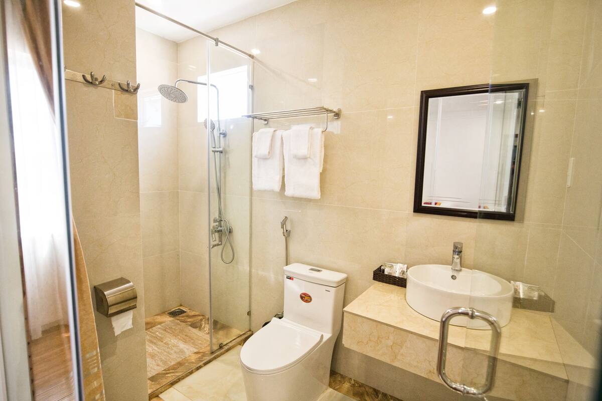 Un baño moderno con ducha envuelta en vidrio, inodoro, lavamanos y espejo.