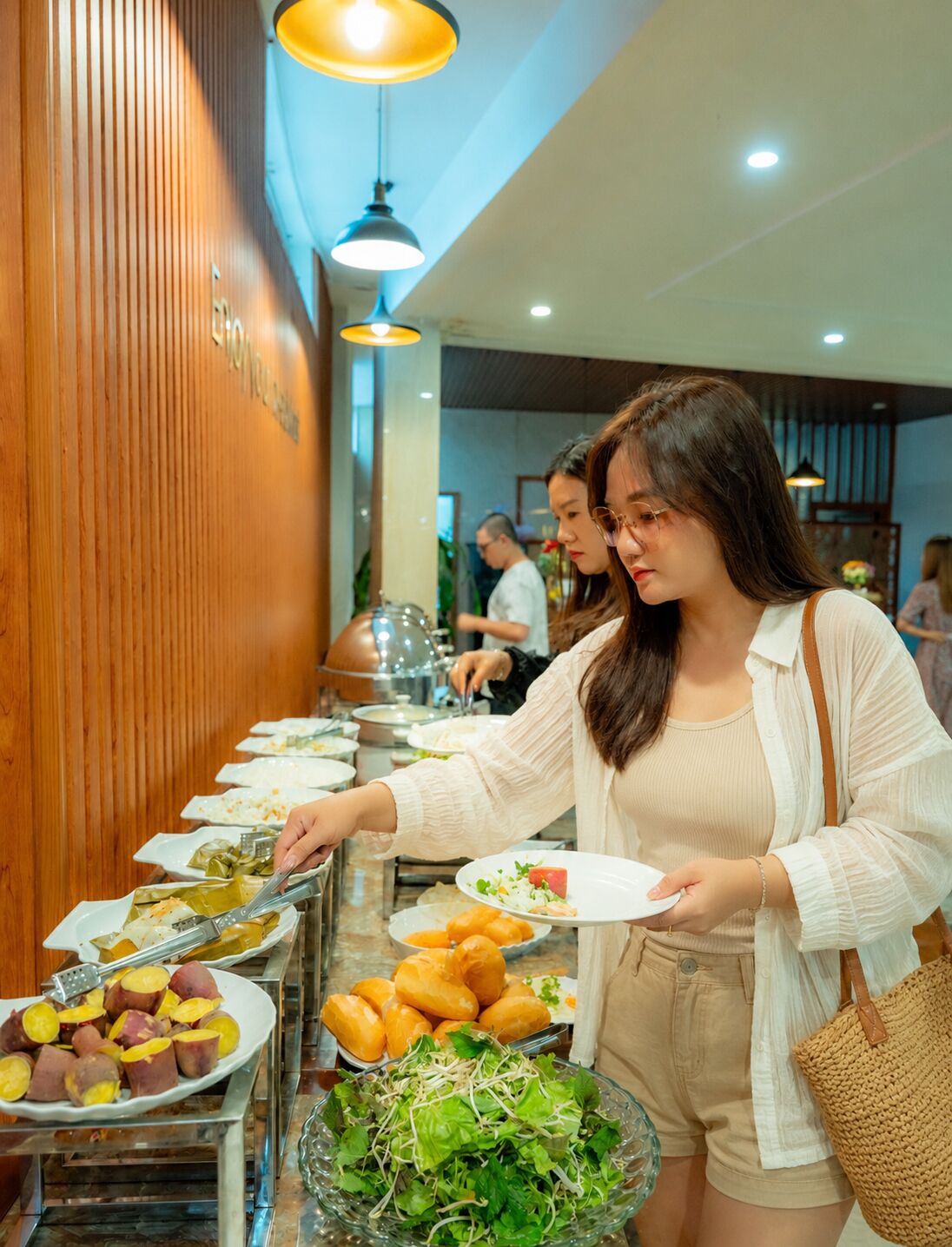 A buffet setup with various food items and a salad bowl.