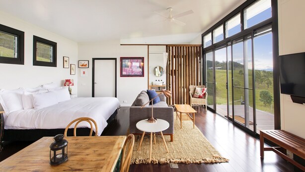 A modern bedroom with a large bed, a sofa, a dining table, and a TV. - “A Secret place to slow down” (Gloucester)
