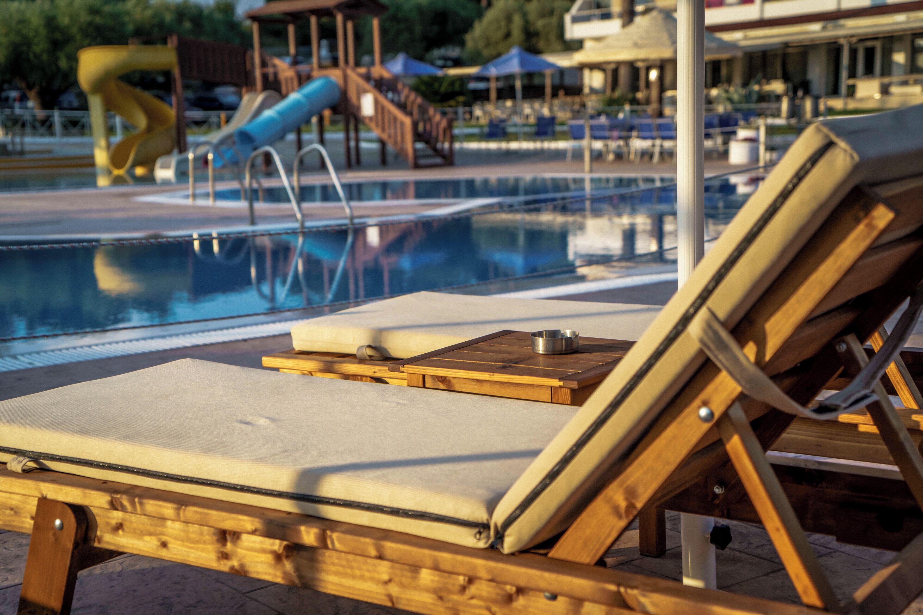 A poolside area with lounge chairs and a slide.