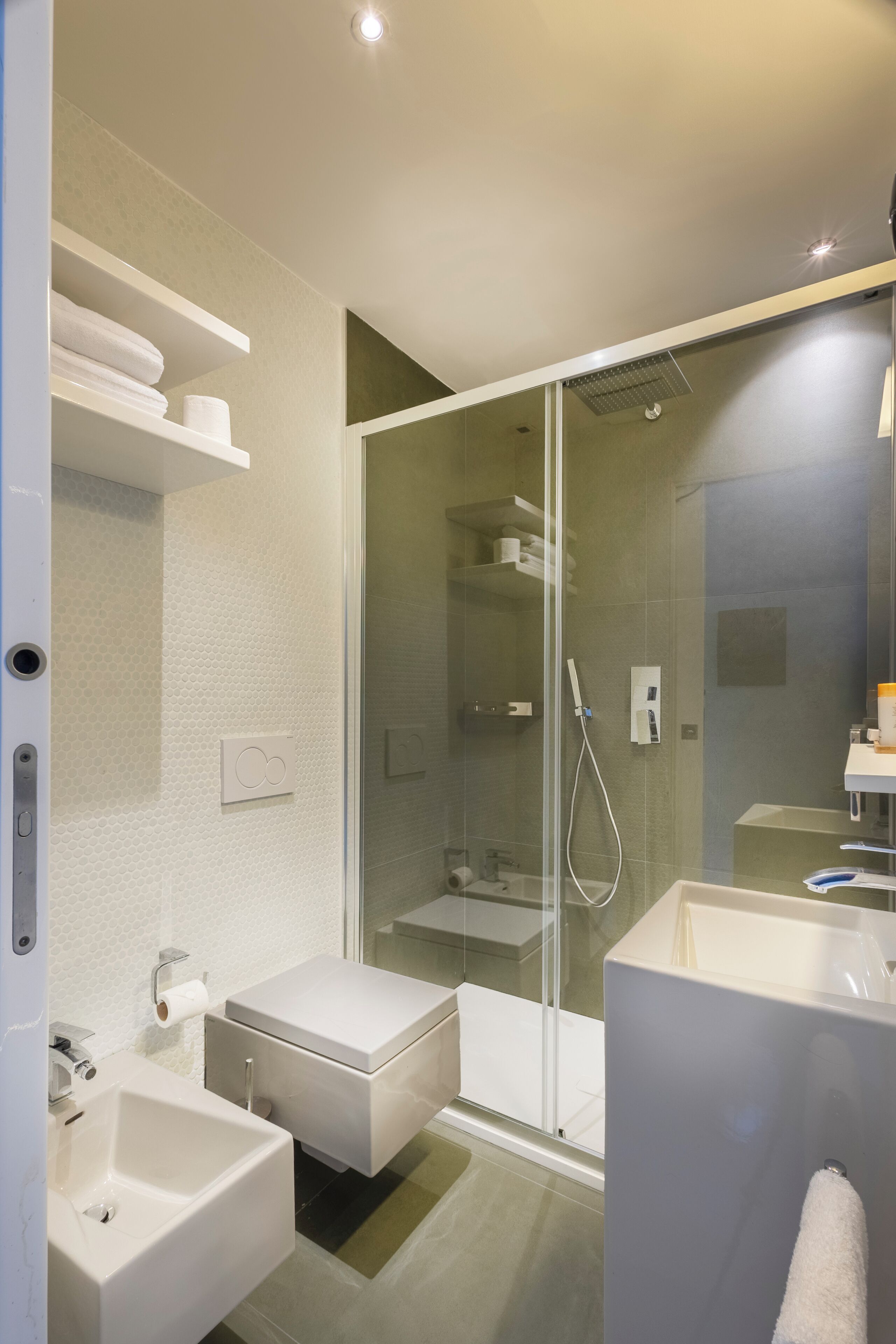 A modern bathroom with a glass-enclosed shower, a white sink, and a large mirror.