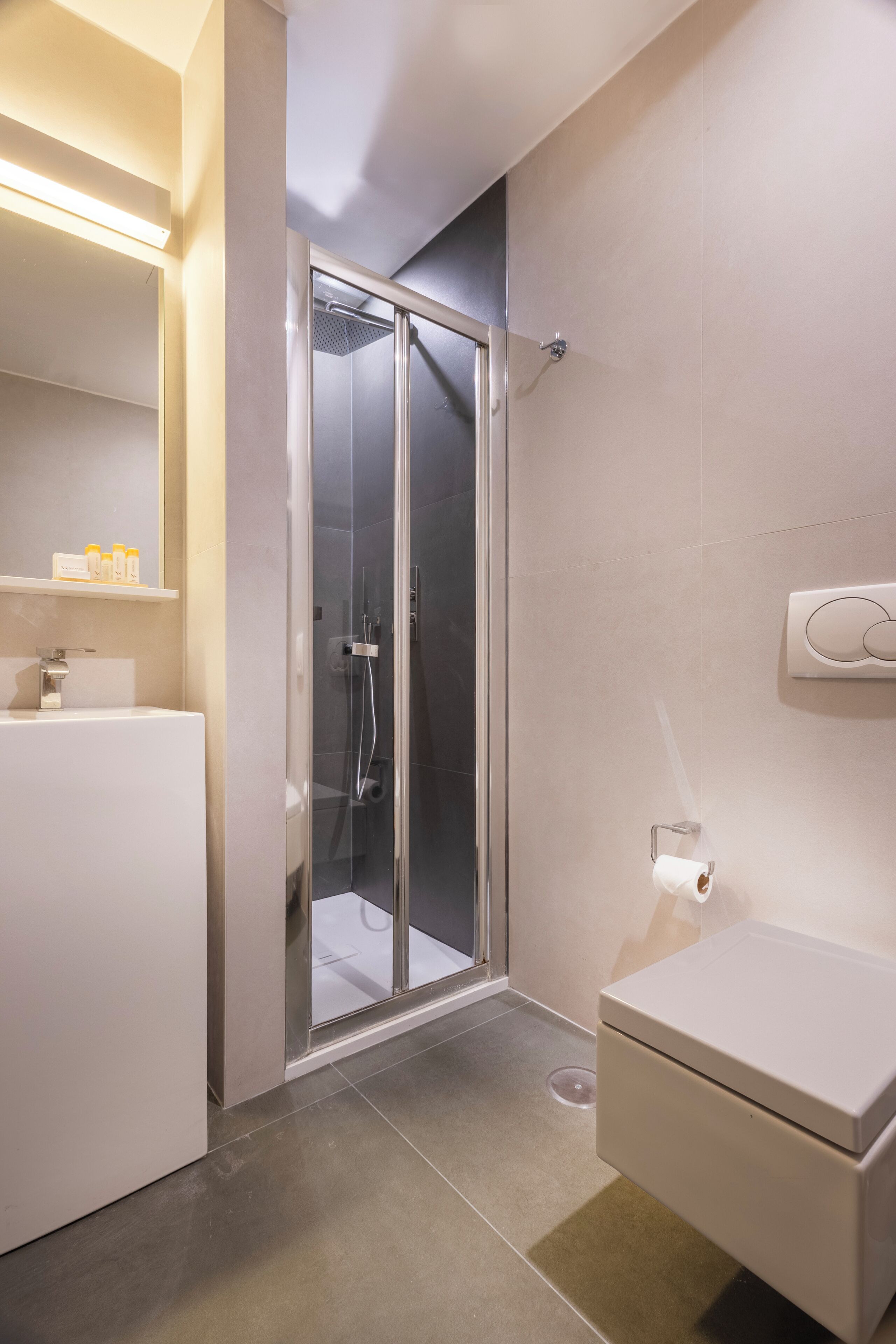 Un baño moderno con ducha de vidrio, inodoro y lavabo con espejo.