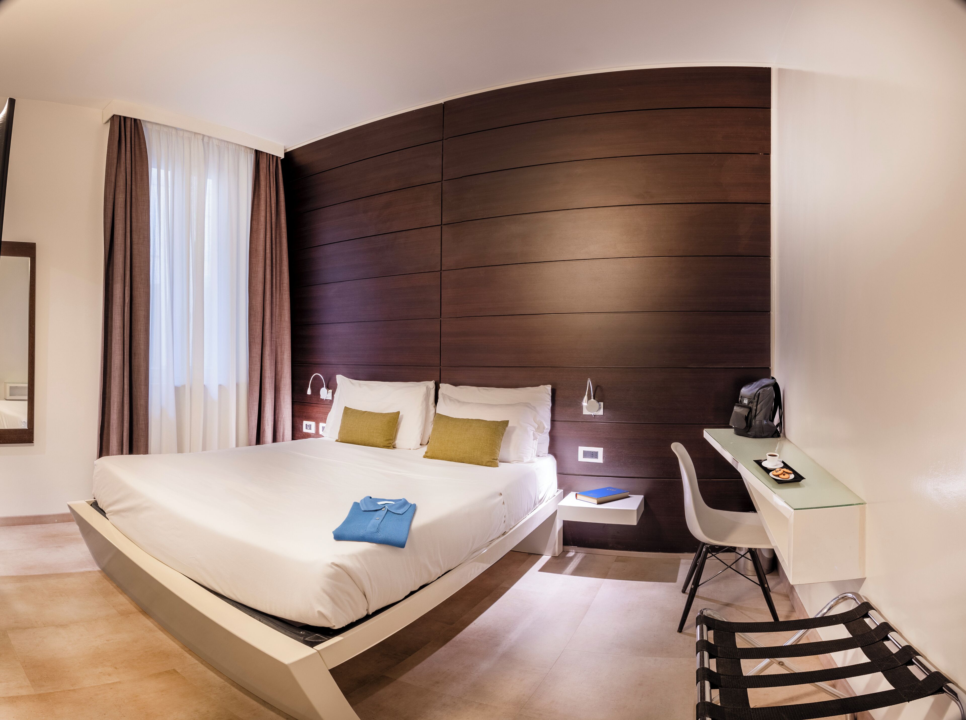 A modern hotel room with a large bed, a desk, and a chair.