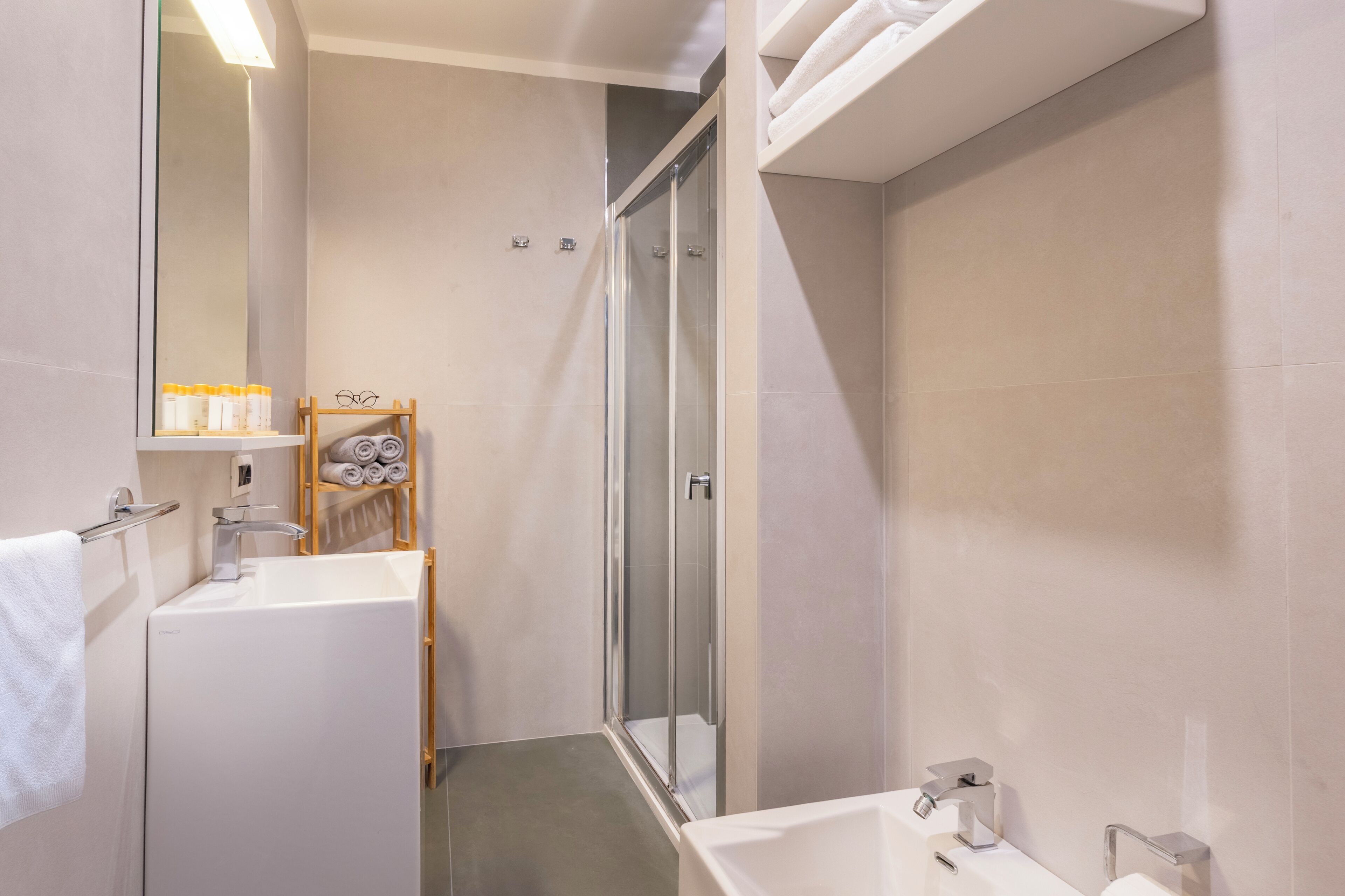 A modern bathroom with a glass-enclosed shower, a white sink, and a mirror.