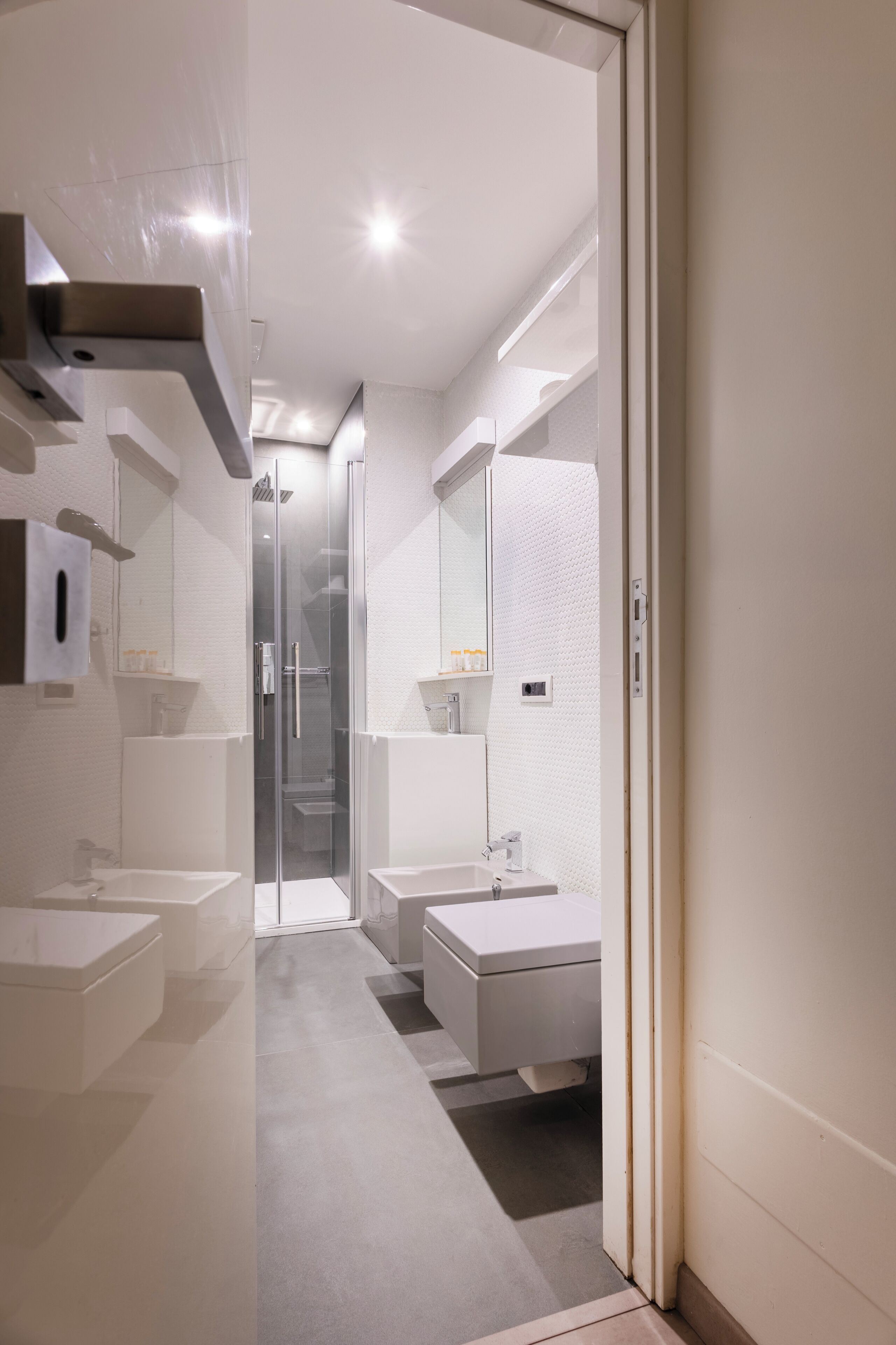 A modern bathroom with a glass shower enclosure, two sinks, and a mirror.