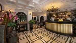 Un hall d’hôtel avec un comptoir d’accueil, un sol à motifs et un plafond décoratif.