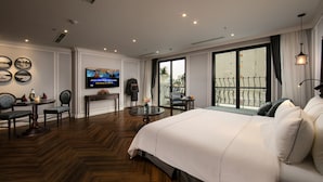 Une chambre d’hôtel avec un grand lit, une télévision, une table à manger avec des chaises et un balcon doté d’une balustrade.