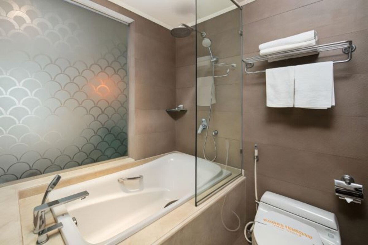 A modern bathroom with a glass-enclosed shower, a bathtub, and a toilet.