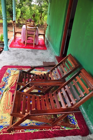 A room with a wooden chair and a table set on a colorful rug. - wish prabha lake view lodge (Sigiriya)