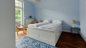 A bedroom with a bed, a chair, a small table, and a lamp. - Imperial Apartments - Winieckiego (Sopot)