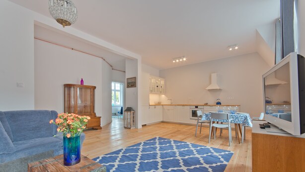 A spacious living area with a sofa, a coffee table with a vase, and a patterned rug. - Imperial Apartments - Winieckiego (Sopot)