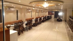 A long dining area with tables and chairs, a chandelier, and a polished floor. - Hotel Royal Amer City (Amer)