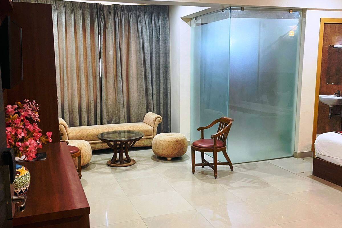 A modern living room with a sofa, a glass door leading to a balcony, a wooden chair, and a ceiling fan.