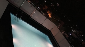 A swimming pool with a clear view of the surrounding buildings and a night sky. - Hotel Royal Amer City (Amer)