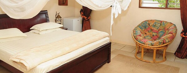 A bedroom with a bed, a nightstand, a lamp, and a chair.