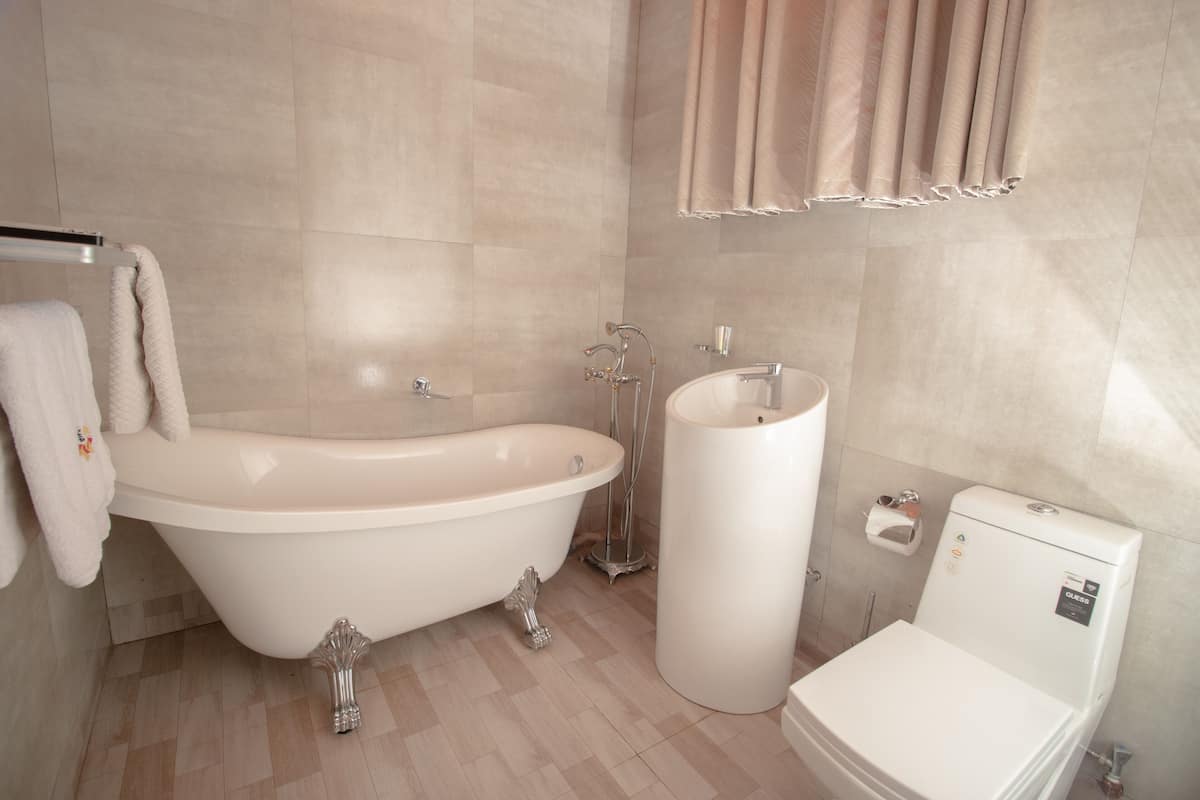 A bathroom with a freestanding bathtub, a pedestal sink, and a toilet.