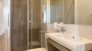 A modern bathroom with a glass-enclosed shower, a white sink, and a mirror above it.