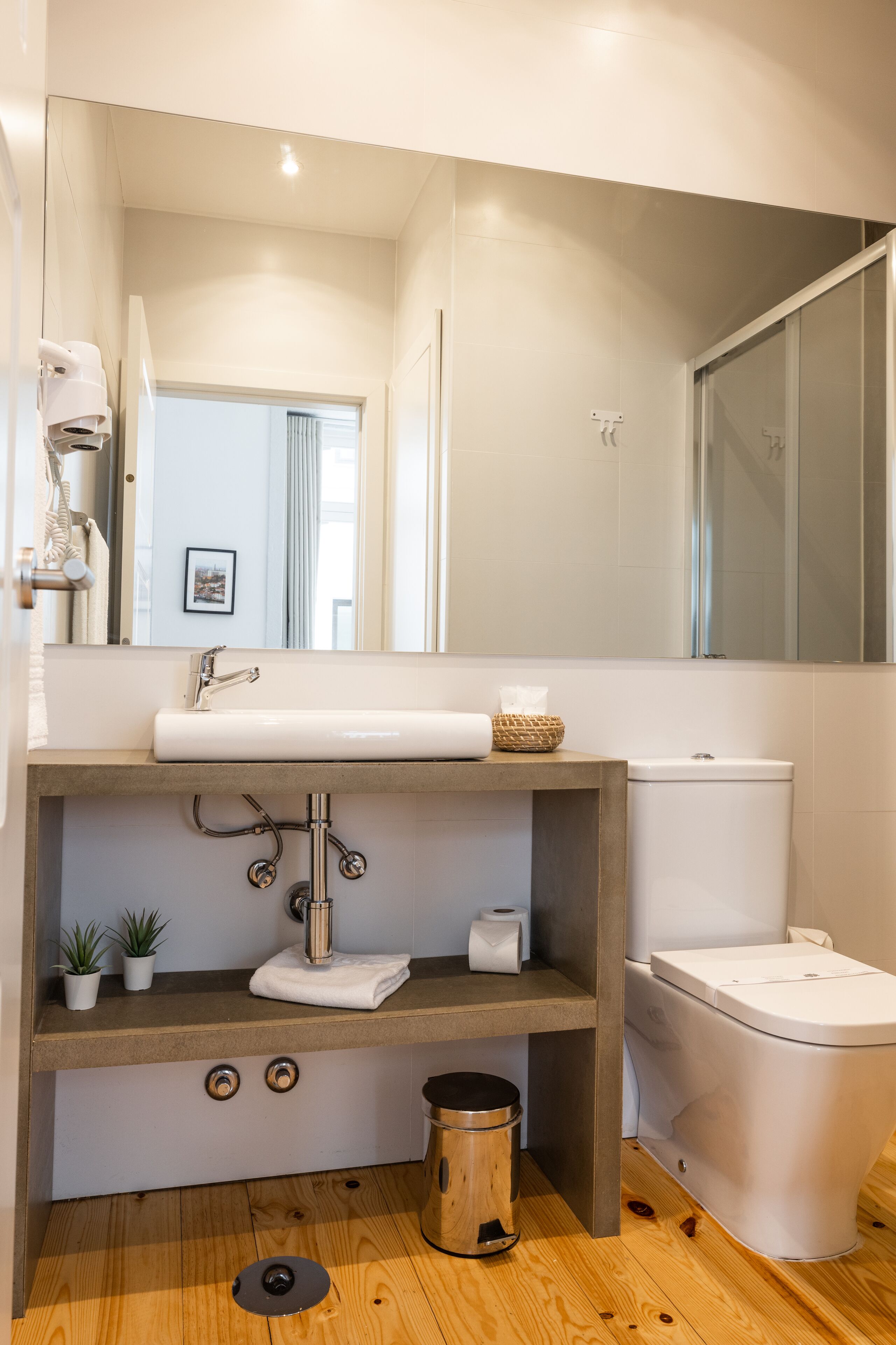 A modern bathroom with a wooden vanity, a white sink, and a toilet.