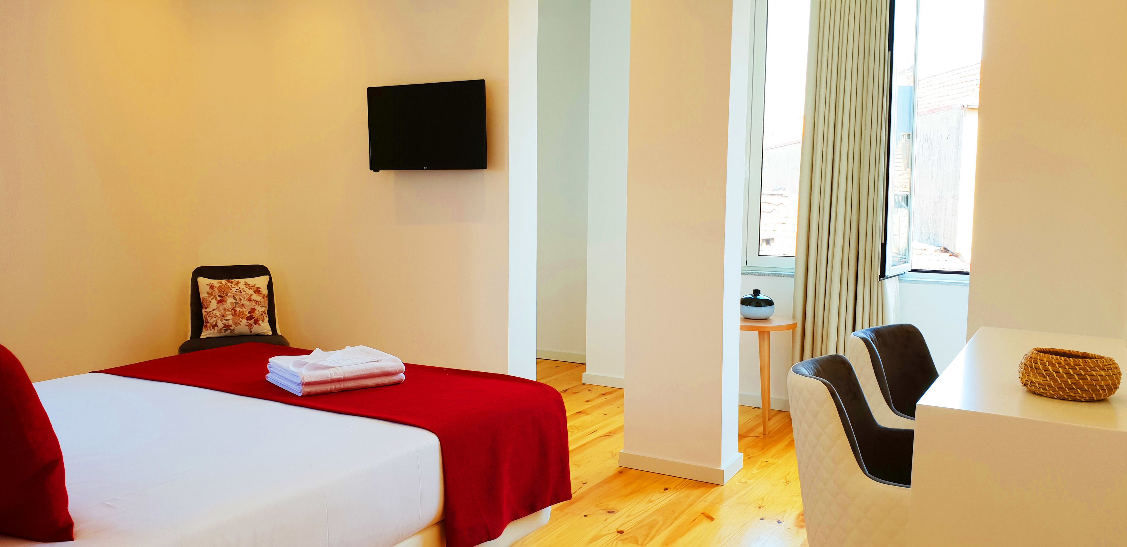 Habitación de hotel con dos camas, un televisor de pantalla plana, una mesita y una ventana con cortinas.