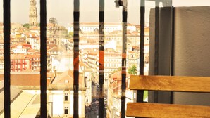 Vista a través de una ventana con baranda de madera, mostrando un paisaje urbano con edificios históricos y una torre destacada.