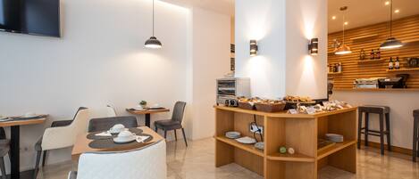 A modern cafe with a central wooden counter, seating area with tables and chairs, and pendant lighting.